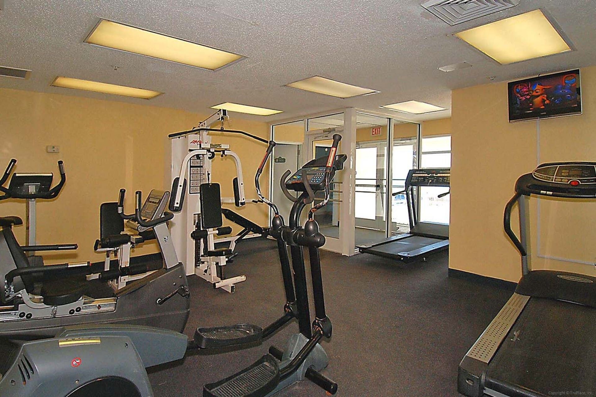 Une salle de sport équipée de divers appareils d’exercice, notamment des tapis de course et des appareils de musculation.
