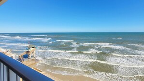 Vista de la playa con olas, una torre de salvavidas y un paseo marítimo de madera.