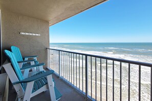A balcony with a view of the ocean, featuring a railing and a row of blue chairs. - Oceanfront 1BR | King Bed | Stunning Views | Sleeps 4 | Free Daily Activities Included (Daytona Beach Shores)