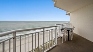 A balcony with a view of the ocean, a table with chairs, and a white railing. - Cozy condo, full kitchen, 2-bedroom | Bay Watch Resort - 1632 (North Myrtle Beach)