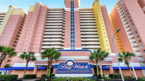 Un hotel de varios pisos con un letrero llamativo que dice "Bay Watch Resort & Conference Center".