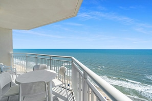 Enjoy the ocean view from this balcony with a round table and two chairs.