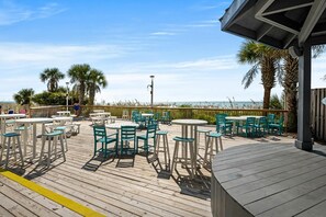 Enjoy a scenic view of the beach from this outdoor deck with comfortable seating and tables.