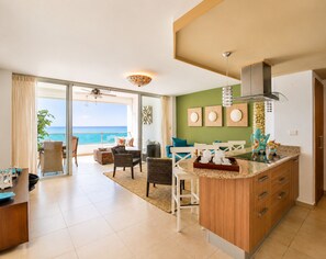 A spacious living area with a balcony overlooking the ocean, a kitchen with wooden cabinets, and a dining area with a table and chairs.