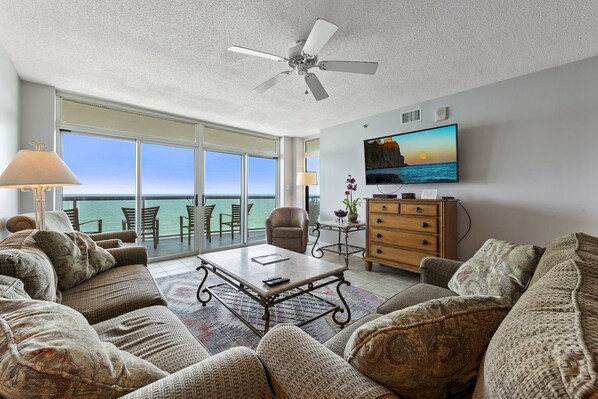 Relax in this ocean-view living room with a ceiling fan, flat-screen TV, and comfortable seating area.