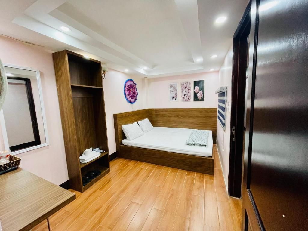 A bedroom with a bed, a wardrobe, a small table, and a refrigerator.