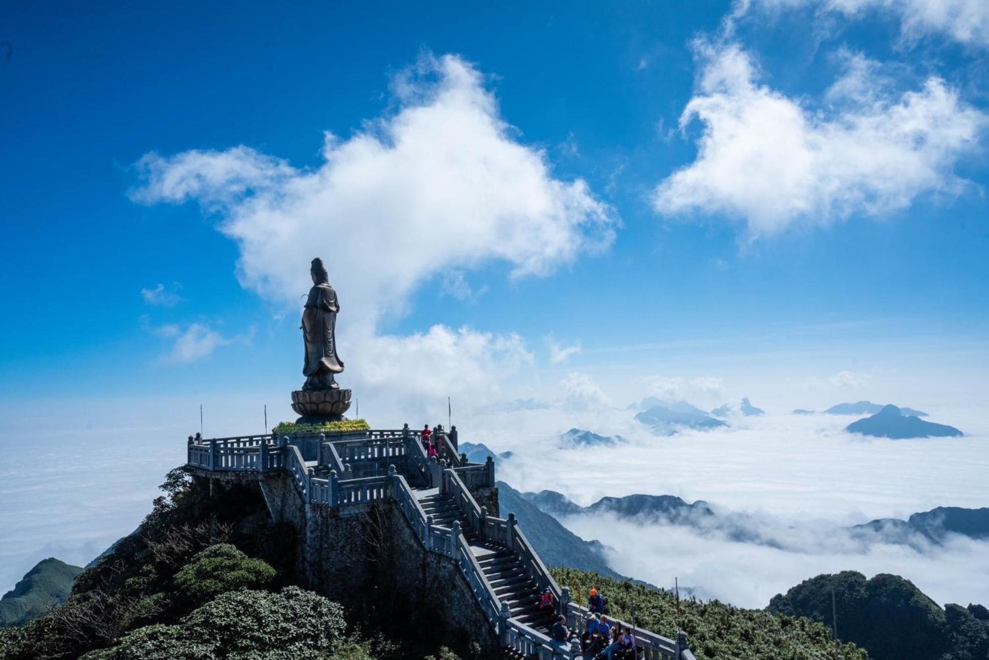 Una estatua en la cima de una montaña con una escalera que lleva hasta ella.