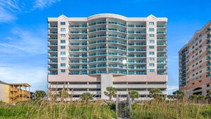 A multi-story hotel with a curved facade, balconies, and a central entrance with a staircase.