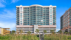 Un hotel de varios pisos con fachada curva, balcones y una entrada central con escaleras.