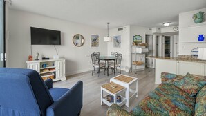 A living room with a TV, dining table, chairs, and a sofa. - Fantastic views from this 1-bedroom oceanfront condo in Carolina Reef! | Carolina Reef -  105 (North Myrtle Beach)