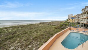 A beachfront view with a pool area, a beach, and a building with multiple balconies. - Fantastic views from this 1-bedroom oceanfront condo in Carolina Reef! | Carolina Reef -  105 (North Myrtle Beach)