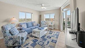 A living room with a blue sofa, patterned armchairs, a coffee table, and a television. - This is a perfect 2-bedroom condo for a vacation at the seaside! | Crescent Keyes -  901 (North Myrtle Beach)