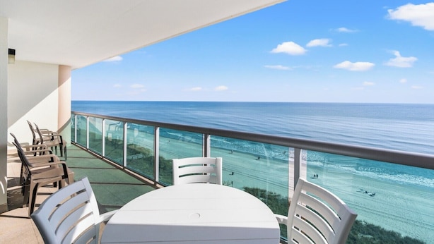 A balcony with a view of the ocean, equipped with a table and chairs.