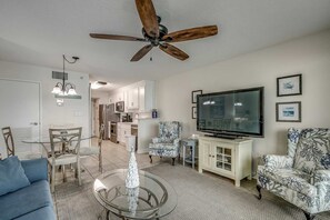 Un salon doté d’un ventilateur de plafond, d’un téléviseur et d’un coin repas avec des chaises et une table.