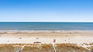 Una playa con cielo despejado, orilla de arena y una torre de salvavidas.