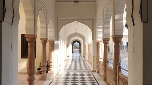 A corridor with arches, a checkered floor, and columns. - The Jaibagh Palace (Amer)