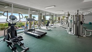 A gym with treadmills, elliptical machines, and weight equipment, overlooking a scenic view.