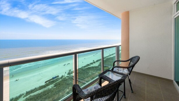 A balcony with a view of the ocean and a beach.