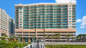 A multi-story hotel with a curved facade, balconies, and a covered walkway. - The stunning view is king in this Crescent Keyes oceanfront condo! | Crescent Keyes - 1008 (North Myrtle Beach)