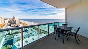 Un balcon avec une table et des chaises, donnant sur une plage et offrant une vue sur la ville.