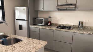 Condo Deluxe, vista parcial al océano | Cocina privada | Refrigerador con congelador, microondas y parrilla de estufa 