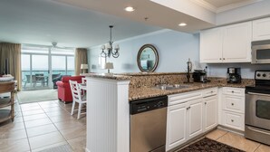 A modern kitchen with white cabinetry, granite countertops, and stainless steel appliances. - Ultra stylish 3-bedroom 3-bathroom oceanfront condo | Crescent Keyes - 908 (North Myrtle Beach)