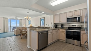 A modern kitchen with a central island, stainless steel appliances, and a view to the outside.