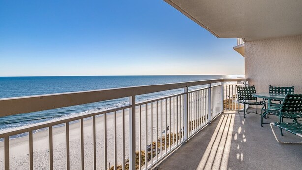 Ein Balkon mit Blick auf das Meer, einem Tisch und zwei Stühlen.
