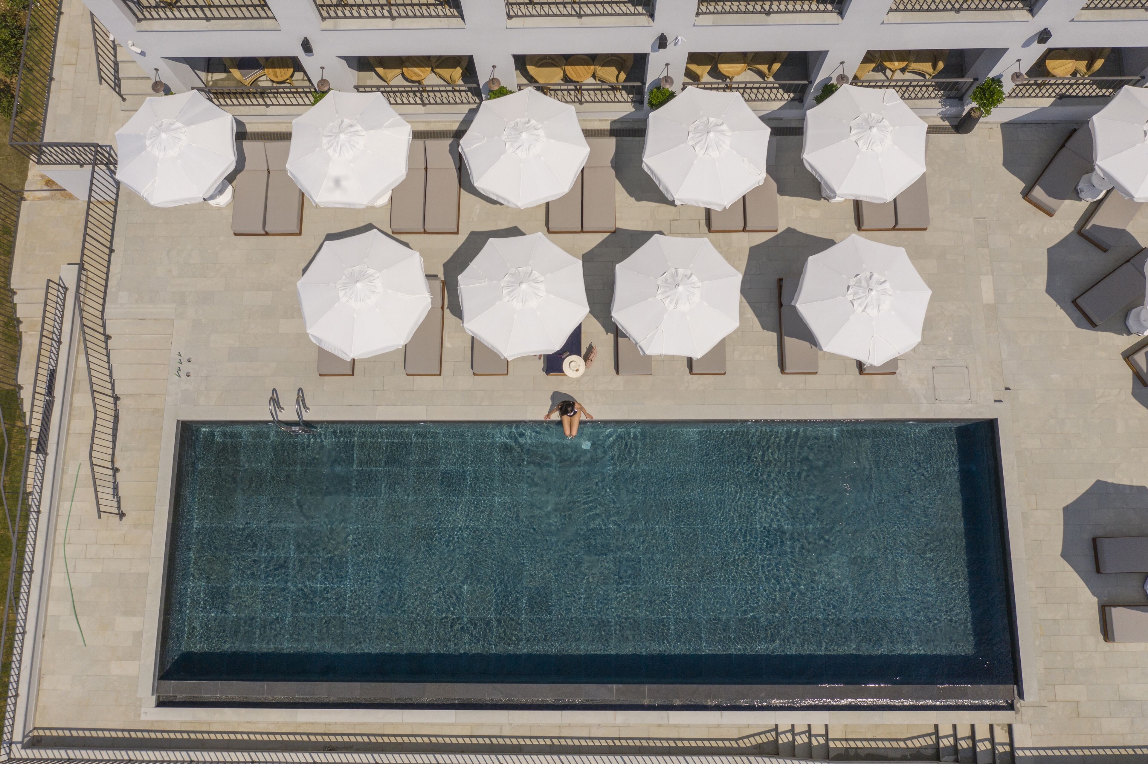 Vista aérea de una piscina con sillas de descanso y sombrillas.