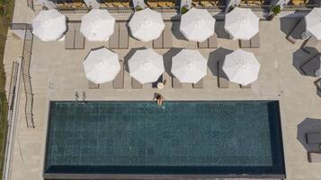 Vista aérea de una piscina con sillas de descanso y sombrillas.