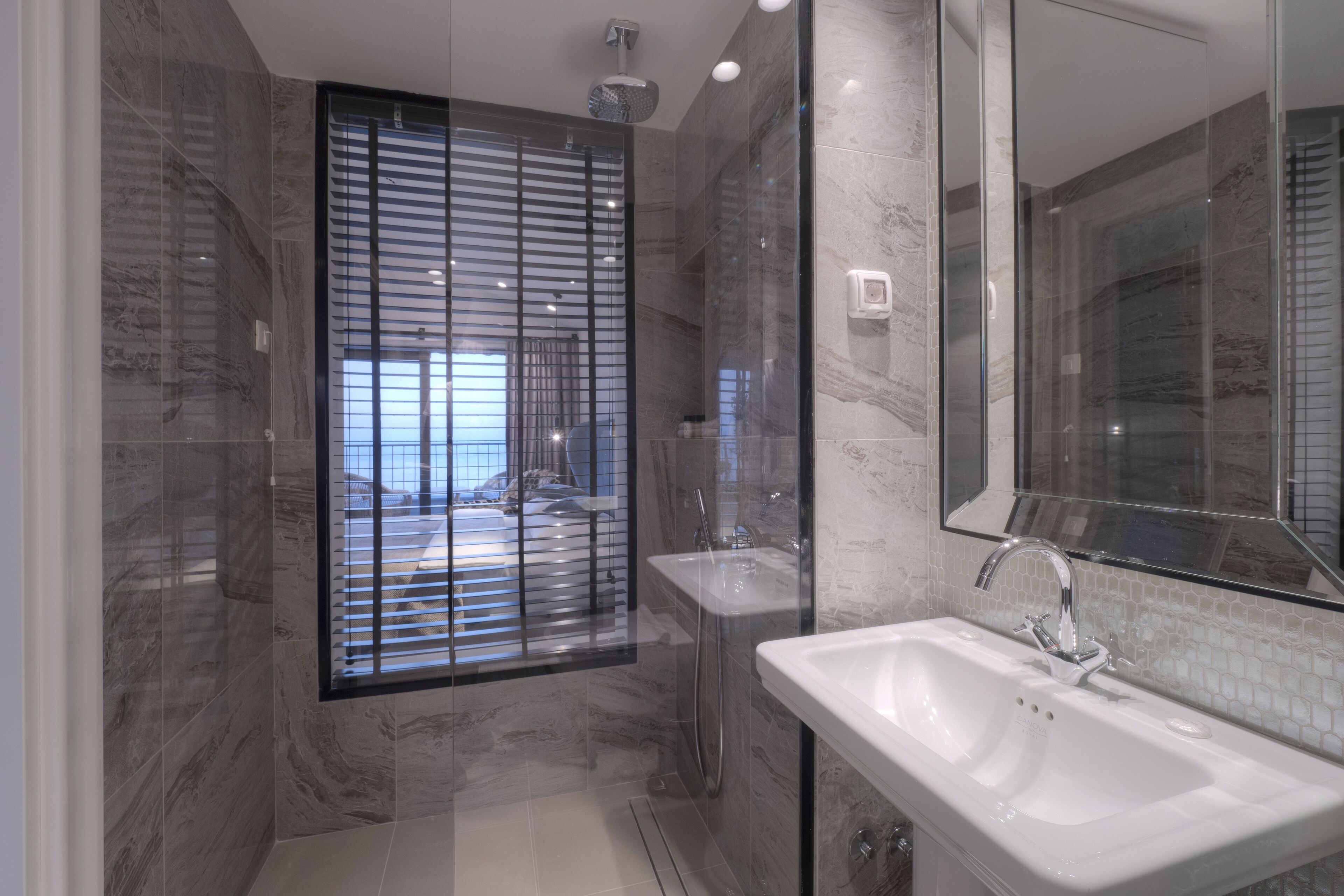Un baño moderno con cabina de ducha de vidrio, un espejo grande y un lavabo blanco.