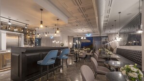 A modern bar area with a counter, bar stools, and a seating area with tables and chairs. - Vivid Blue Serenity Resort (Petrovac)