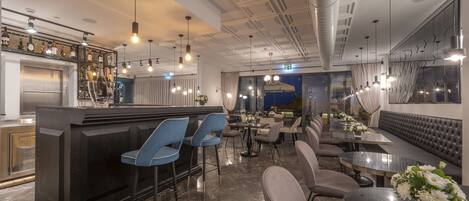 A modern bar area with a counter, bar stools, and a seating area with tables and chairs.
