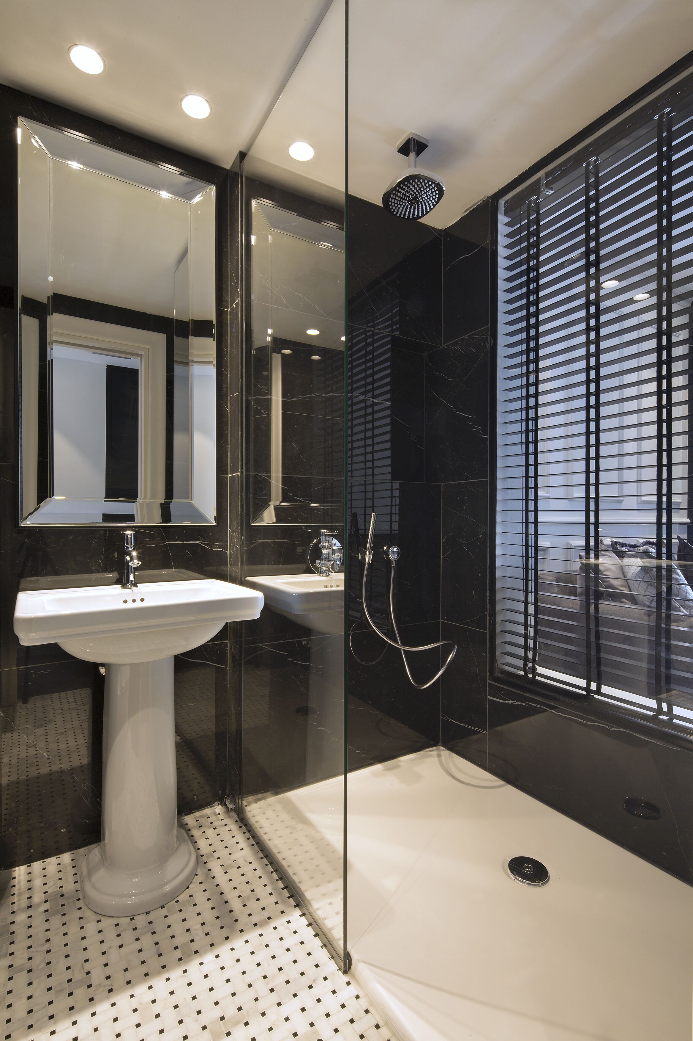 Une salle de bain moderne avec un lavabo sur pied blanc, une douche à parois de verre et un grand miroir.