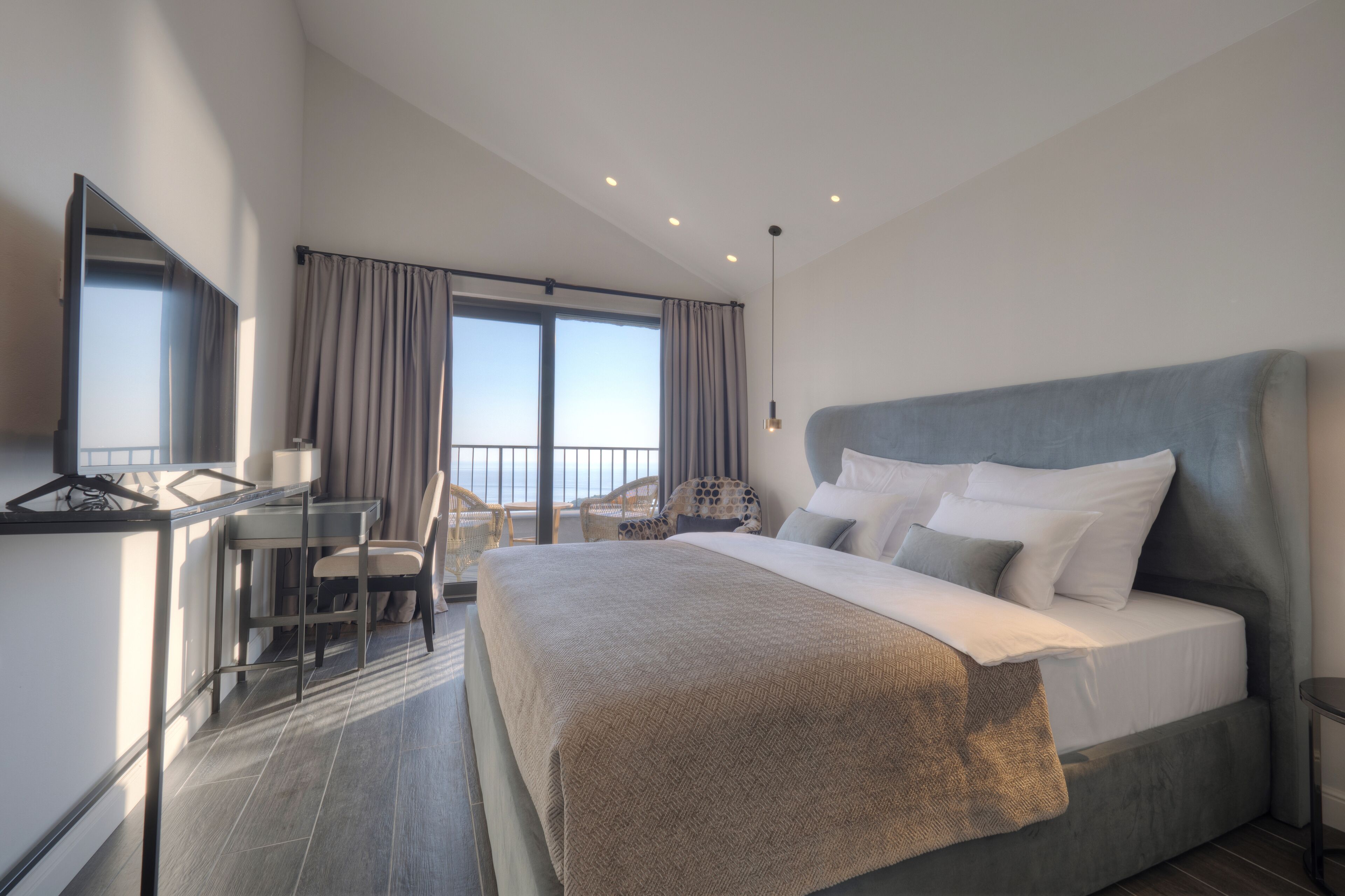 A modern hotel room with a large bed, a desk, and a chair.