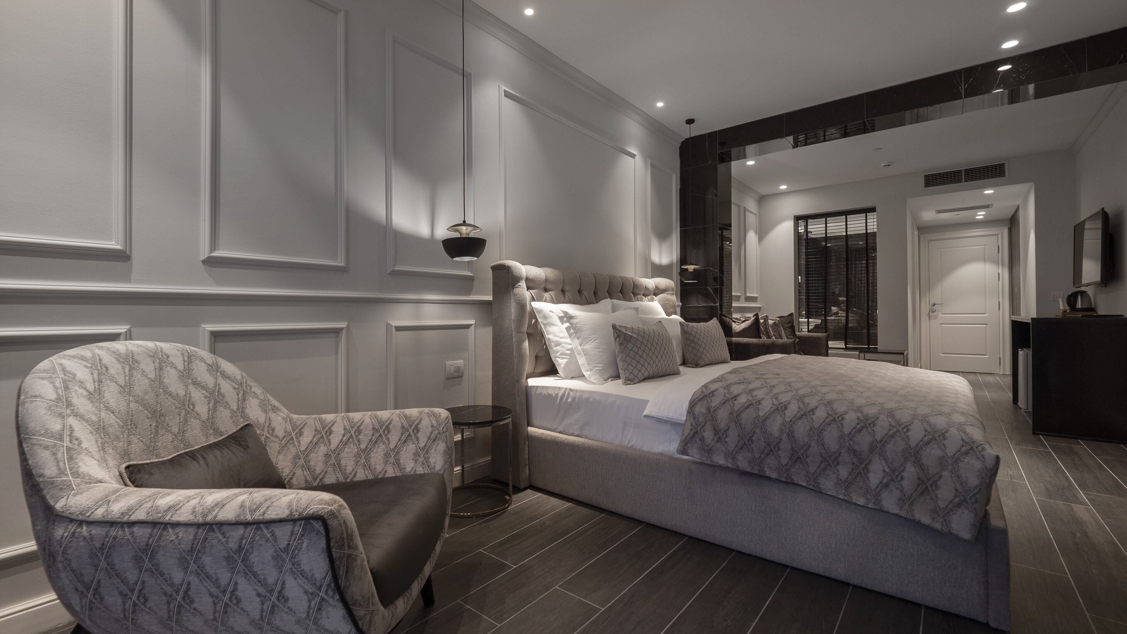 A modern bedroom with a large bed, a chair, and a dresser.