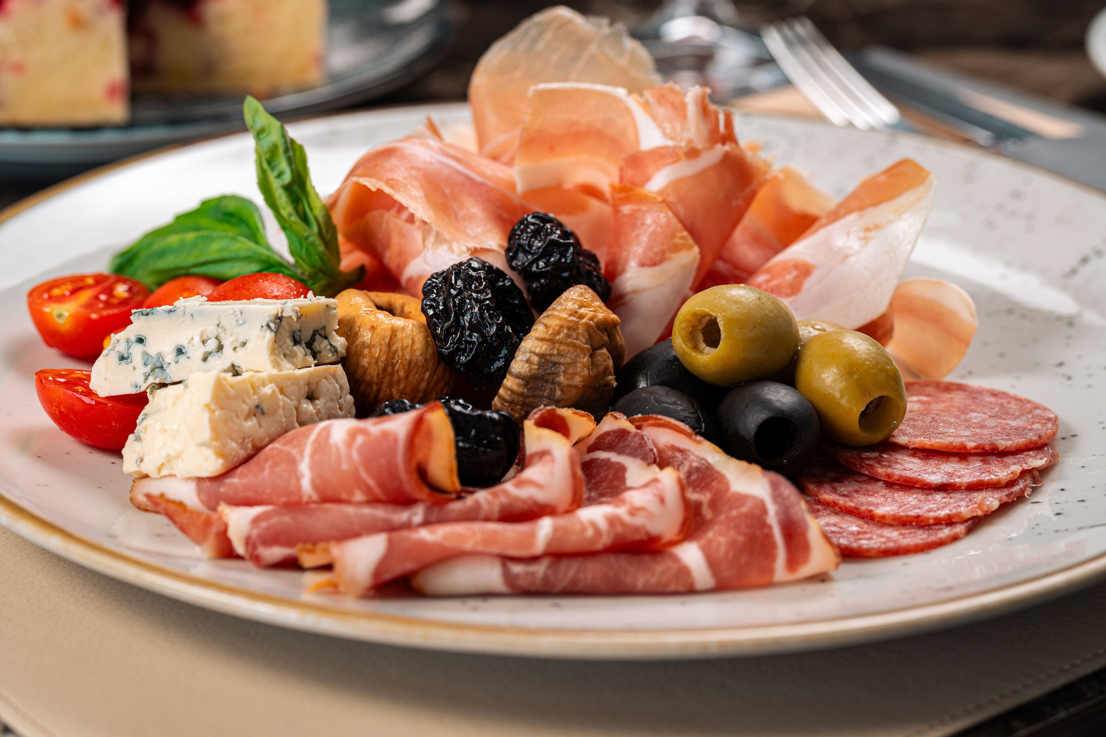 Une assiette de charcuteries variées, d’olives et de fromage.
