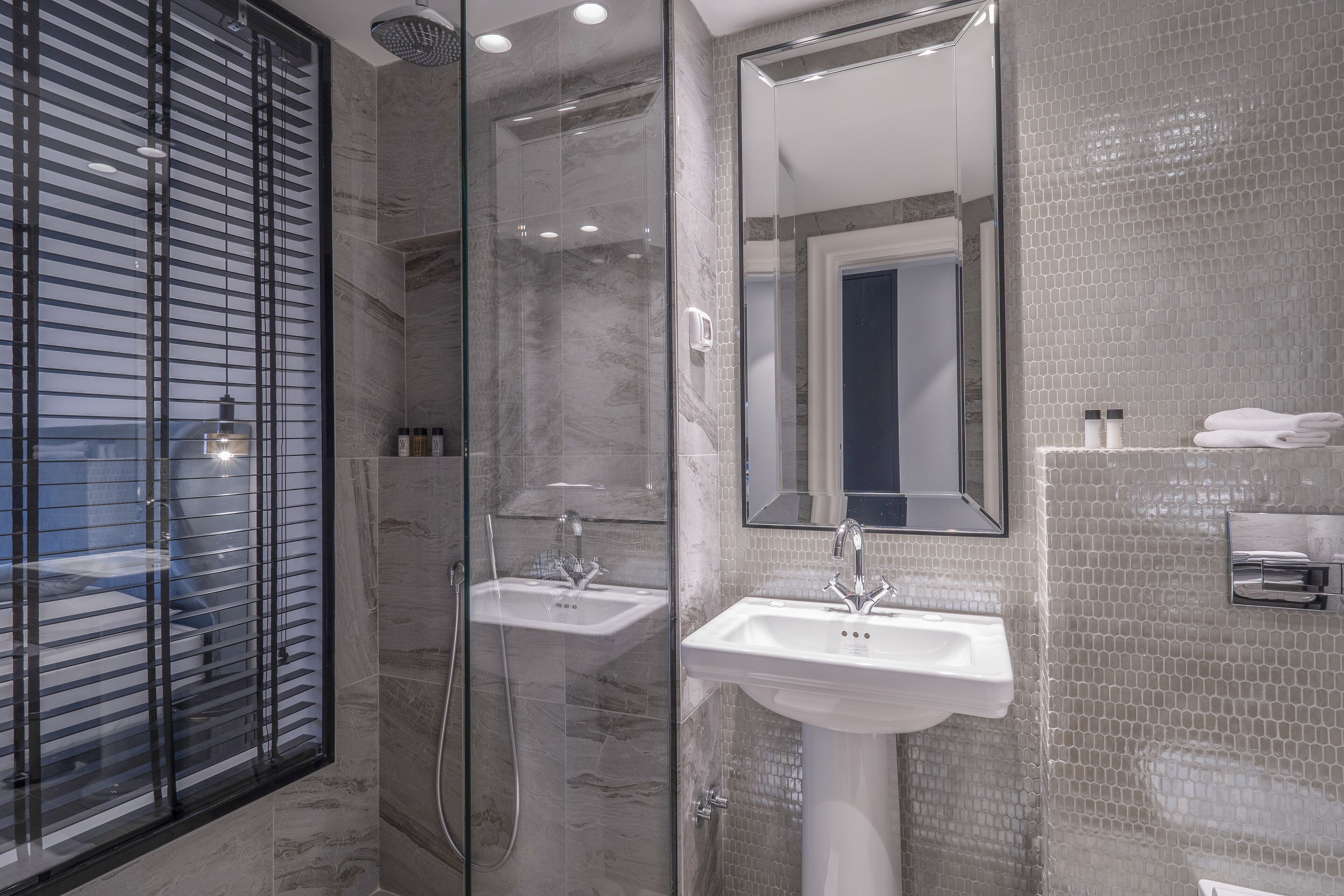 Une salle de bain moderne dotée d’une douche à parois de verre, de deux lavabos et d’un grand miroir.