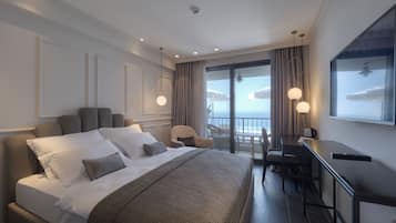 Habitación de hotel con una cama grande, un escritorio y un balcón con vistas.