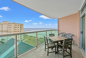 Enjoy the ocean view from this balcony with a table and chairs.
