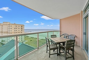Enjoy the ocean view from this balcony with a table and chairs.