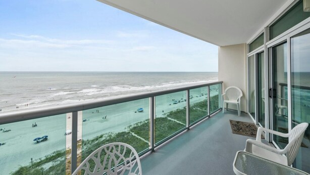 Ein Balkon mit Blick auf das Meer, einem Stuhl und einem Tisch.