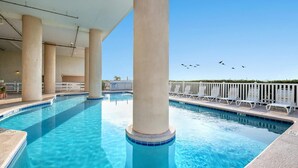 Ein Swimmingpool mit klarem, blauem Wasser, umgeben von weißen Liegestühlen und einem weißen Zaun.