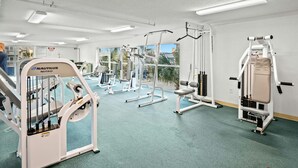 Een fitnessruimte met Nautilus-apparatuur, grote ramen en een groen tapijt.