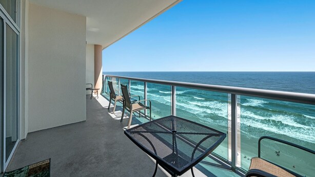 Un balcon avec vue sur l’océan, une table et deux chaises.