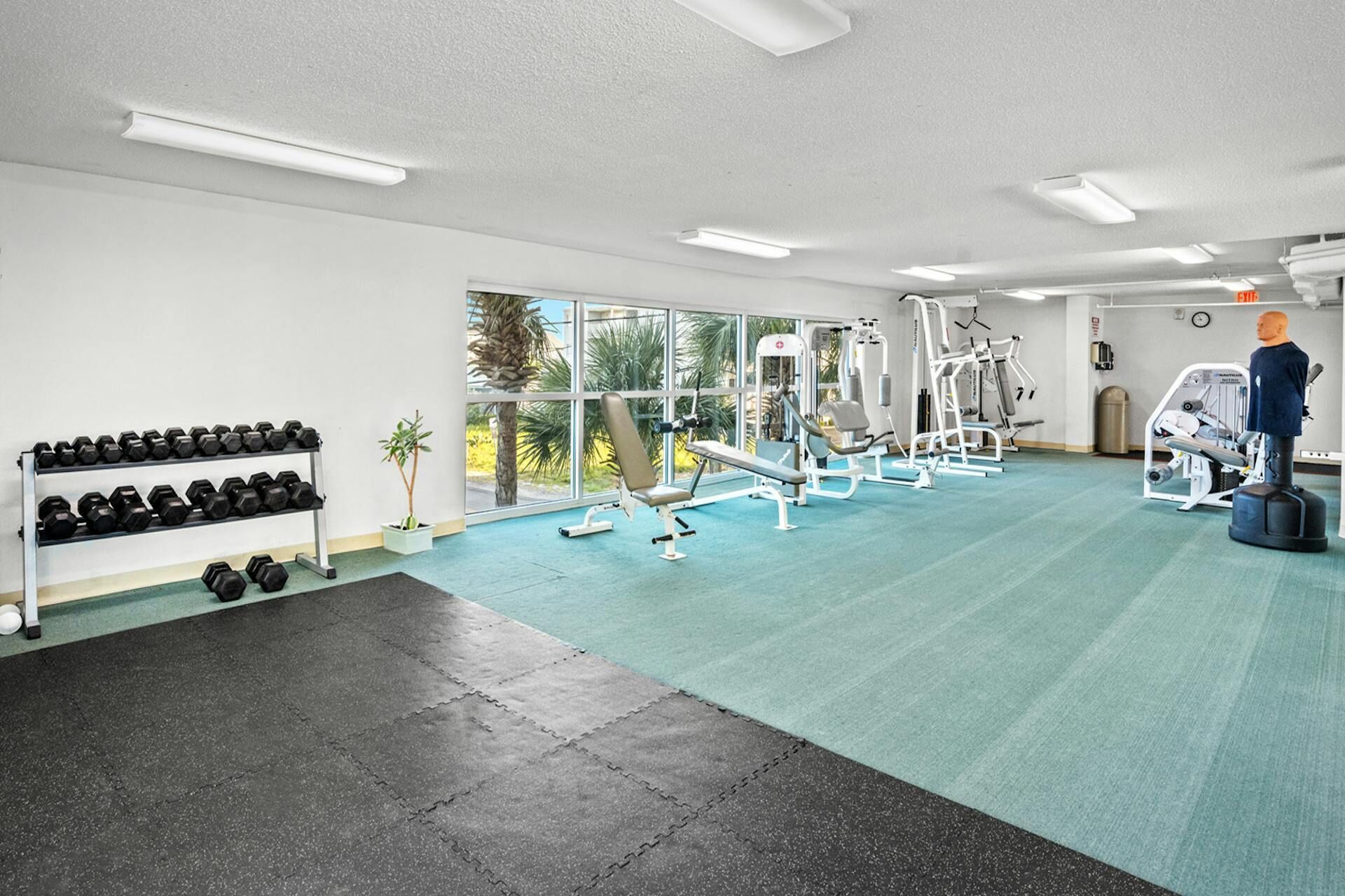 Ein Fitnessraum mit Trainingsgeräten, einer Schaufensterpuppe und einem Hantelständer.