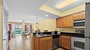 A compact kitchen with wooden cabinets, stainless steel appliances, and a dining area with a sofa and chairs.