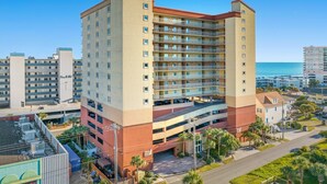 A multi-story hotel with a central courtyard, balconies, and a view of the ocean.