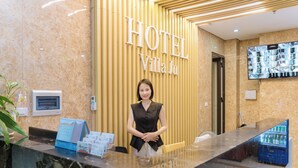 A hotel reception desk with a marble counter, a digital screen, and a vending machine. - Hotel Villa Ju (Hanoi)