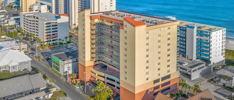 A high-rise hotel with multiple floors, a parking garage, and a view of the ocean.